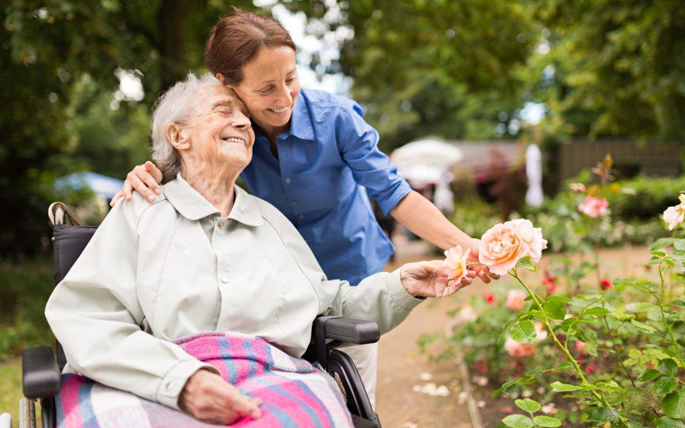 Senior woman sitting on a wheelchair with caregiver