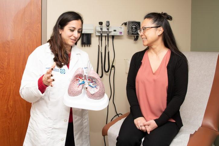 Dr. Avneet Singh discusses a model of the lungs with a patient